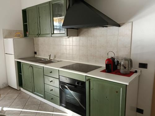 a kitchen with green cabinets and a stove top oven at Casa Arcobaleno Holiday home apartments in Diano dʼAlba