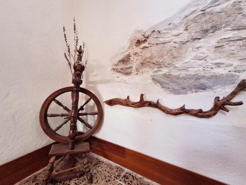 a wooden spinning wheel next to a wall with a painting at Nuragic Temple in Esterzili