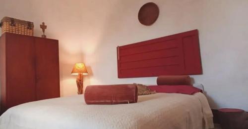 a bedroom with a large white bed with a red headboard at Nuragic Temple in Esterzili