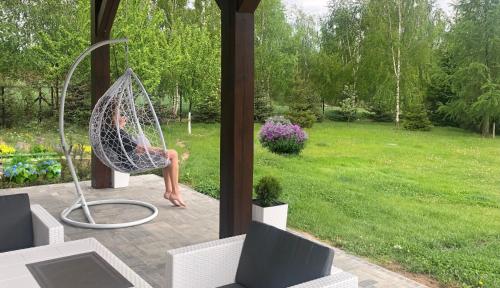 a woman sitting in a hammock in a yard at Uroczy duży dom nad jeziorem z prywatną przystanią in Steklinek