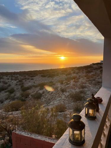 a view of the sunset from a porch with two lights at Suite privée vue sur le océan in Wassane