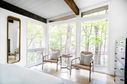 a bedroom with a bed and two chairs and a mirror at Private Cabin by River with Fireplace in Phoenicia