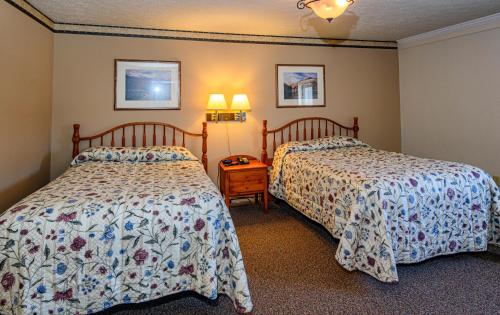 Un dormitorio con dos camas y una mesita de noche. en Westgate Inn, en Coudersport