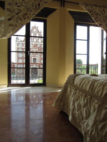 a bedroom with large windows and a bed in a room at Casa de los Pianos in Uaymá