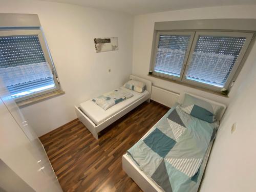 een kleine kamer met een bed en twee ramen bij Unterkunft 20 Eibach in Neurenberg