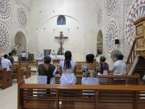 a group of people sitting in a church at Casa de los Pianos in Uaymá