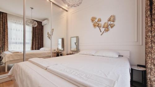 a white bedroom with a large bed and a mirror at White Pearl, Casa Al Mare in Rafailovici