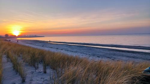 a beach with the sun setting over the water at Ferienwohnung OstseeBlick Rerik in Rerik