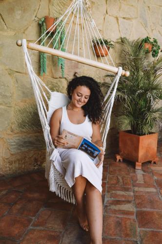 a woman sitting in a hammock reading a book at Hotel Boutique Casa Encanto Barichara in Barichara
