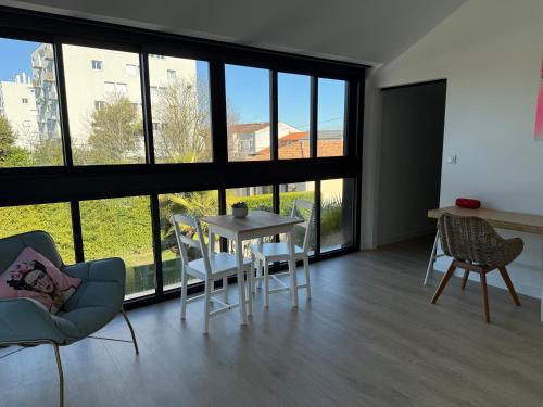 a living room with a table and chairs and large windows at Poolside Retreat in Le Bouscat in Le Bouscat