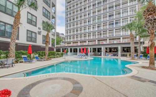 a swimming pool in front of a building with palm trees at A Taste of Greece -1BR - NRG - MD Anderson - Galleria in Houston