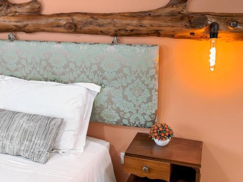 a bedroom with a bed with a wooden headboard and a table at Ninho D'Arara in Tondela