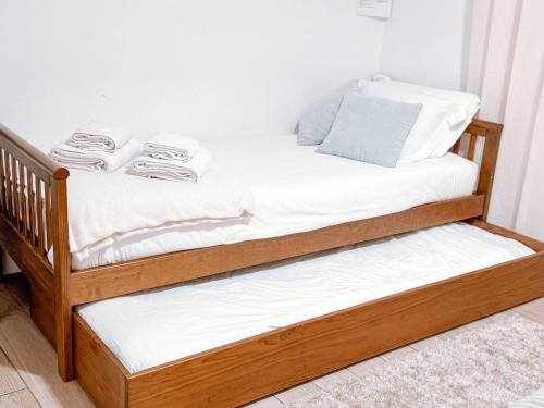 a wooden bunk bed with white sheets on it at Ninho D'Arara in Tondela