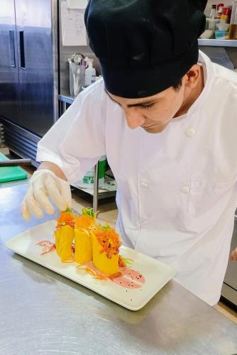 a chef preparing a plate of food in a kitchen at Riosol Hotel Tarapoto in Tarapoto