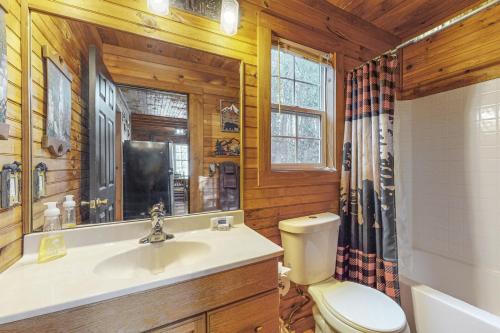 a bathroom with a toilet and a sink and a mirror at Bear’s Den in Sautee Nacoochee
