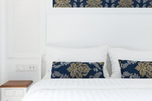 a bedroom with a white bed with blue and gold pillows at White Ivory Bed And Breakfast in Bangkok