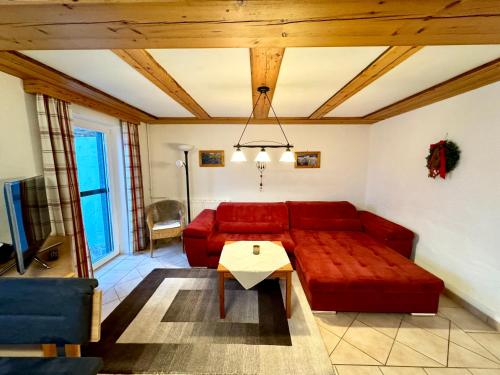 a living room with a red couch and a table at Haus Landzauber in Ramsau am Dachstein