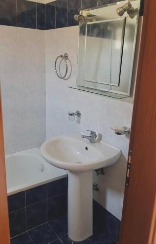 a bathroom with a sink and a mirror and a tub at Family Vacation Home in Gjirokastër