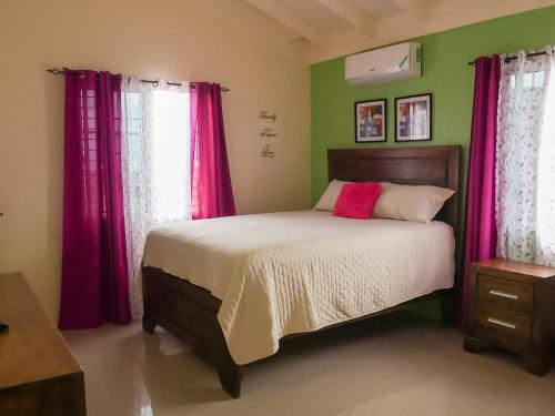 a bedroom with a large bed with pink curtains at 2 BDR House near Martha Brae River rafting in Falmouth