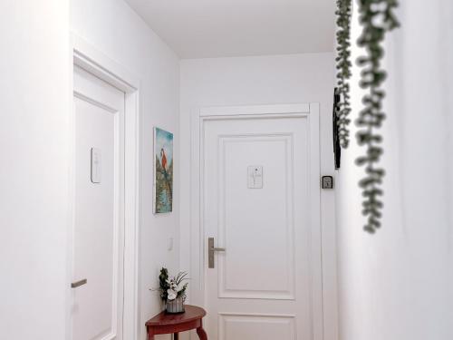 a white hallway with a white door and a table at Ninho D'Arara in Tondela