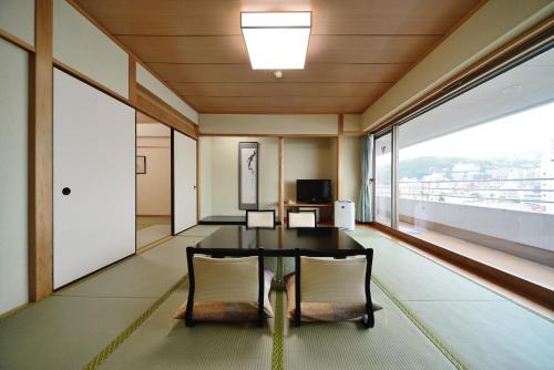 a dining room with a table and chairs and a large window at Hotel Sunmi Club in Atami