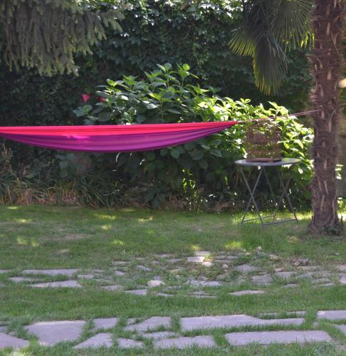 a pink hammock sitting in the grass next to a chair at Al Giardino degli Artisti in Cairo Montenotte