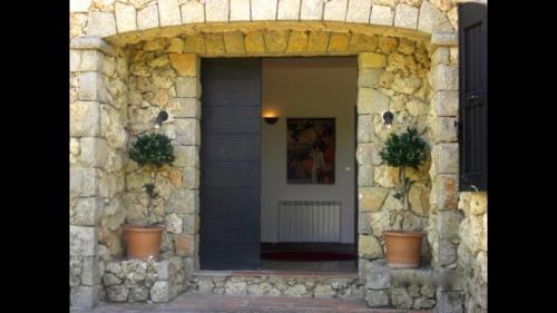 un bâtiment en pierre avec une porte et deux plantes en pot dans l'établissement Luxurious villa with large heated pool in 2 acre private garden Ideally located for visiting Cannes Nice and St Tropez, à Saint-Paul-en-Forêt