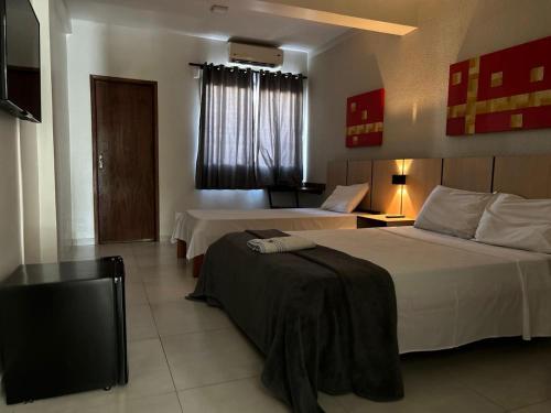 a hotel room with two beds and a television at Hotel JCA Uberlândia in Uberlândia