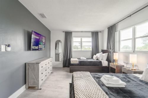 a bedroom with two beds and a dresser and window at Ocean Whisper - Sleeps 11 - Palm Wave Stays in Coconut Creek
