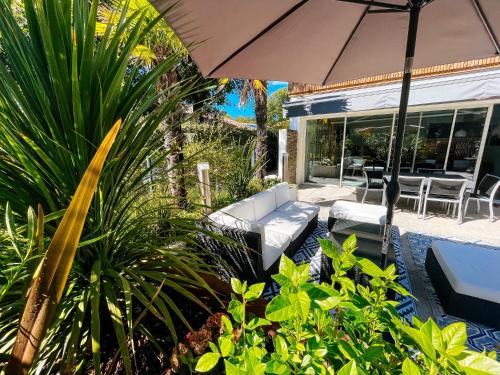 une terrasse avec un parasol, des chaises et des plantes dans l'établissement Appartement Aqua-Villas Lake And Sea, à Seignosse