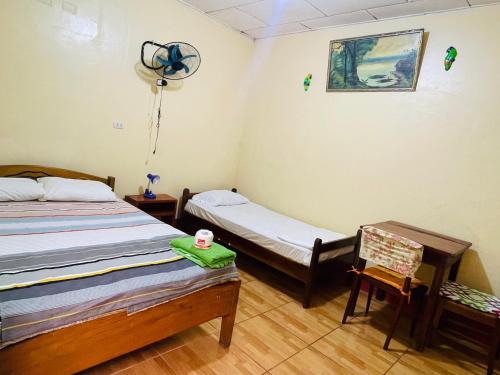 a room with two beds and a chair and a fan at Urcututo House Iquitos in Iquitos