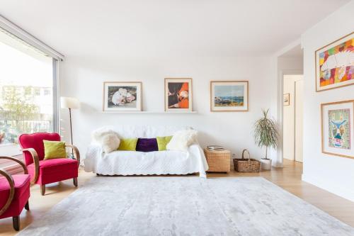 un salon avec un canapé blanc et une chaise rouge dans l'établissement Beautiful Paris Centre apartment in garden, à Paris