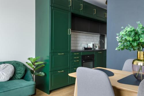 a green kitchen with green cabinets and a table at Kairos Apartments - Royal Premium - parking podziemnym gratis, ścisłe centrum in Gliwice