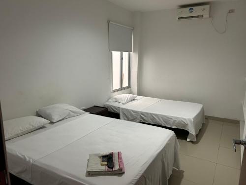 a room with two beds and a window at Hotel Violetas Del LLano in Yopal