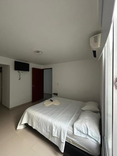 a white bedroom with a bed with white sheets at Hotel Violetas Del LLano in Yopal