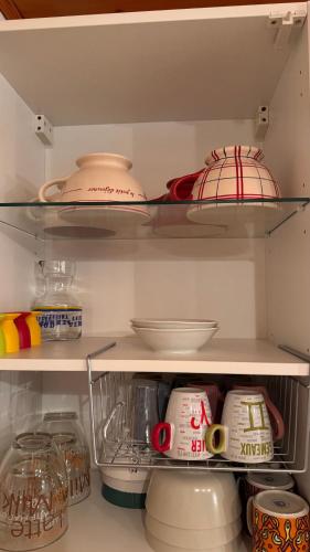 un réfrigérateur rempli de vaisselle et de bols. dans l'établissement En vacances, comme à la maison, à La Joue du Loup