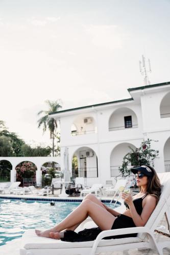 a woman in a black dress sitting on a chair by a pool at Hotel Casablanca Boutique Ciudad del Este By Swiss Bonmont Hotels in Ciudad del Este