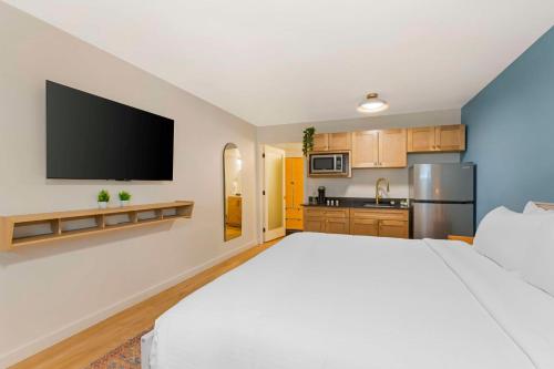a bedroom with a large white bed and a kitchen at The Kennedy Tucson, SureStay Collection by Best Western in Tucson