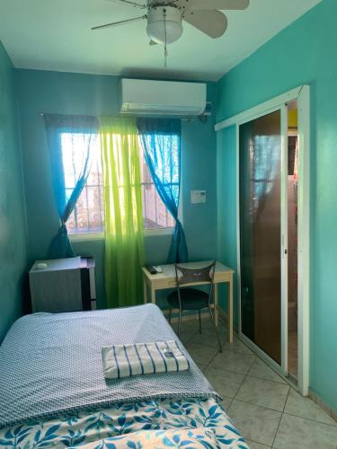 a bedroom with a bed and a desk and a window at Casa Azul - Apartment in San Felipe de Puerto Plata