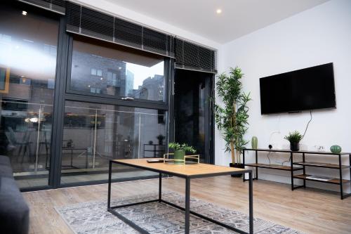 マンチェスターにあるLuxury 2 Bedroom and bathroom in Central Manchester With Balconyのリビングルーム(テーブル、薄型テレビ付)
