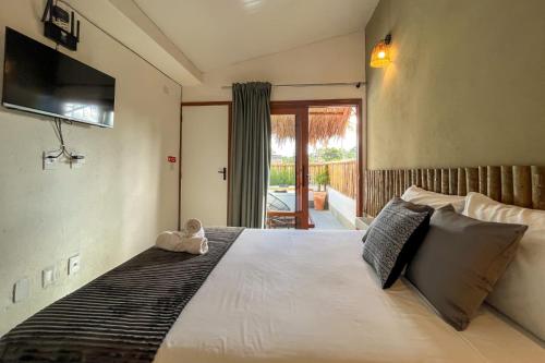 Un dormitorio con una cama con un osito de peluche sentado en ella. en Nomad Palmeira Duplex com Hidromassagem privativa, en Porto de Pedras