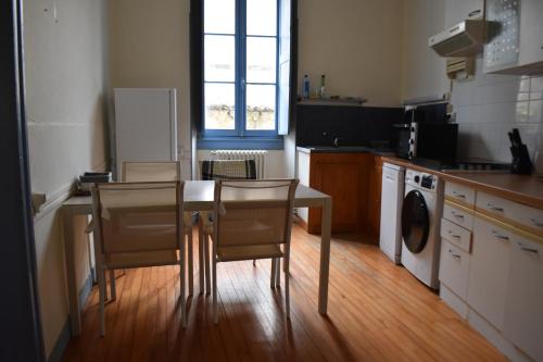 une cuisine avec une table et des chaises dans une cuisine dans l'établissement Appartement de caractère plein centre, à Bourg