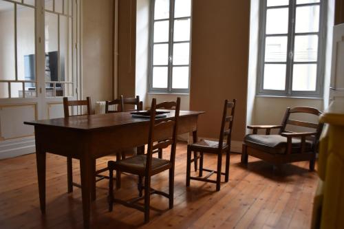 une salle à manger avec une table, des chaises et des fenêtres dans l'établissement Appartement de caractère plein centre, à Bourg