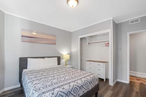 a white bedroom with a bed and a dresser at Escape to Raleigh Ave Glamour - Steps to the Beach in Atlantic City