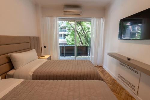a bedroom with two beds and a window at Aparthotel Trianon Recoleta in Buenos Aires