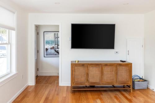 a living room with a flat screen tv on a wall at Sunny 3BR Beach House, Steps to Pine Point Beach in Scarborough