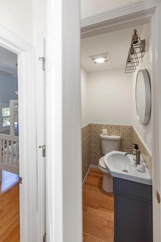 a bathroom with a toilet and a sink and a mirror at 3BR Beach House, Walk to Sand & Sea in Scarborough