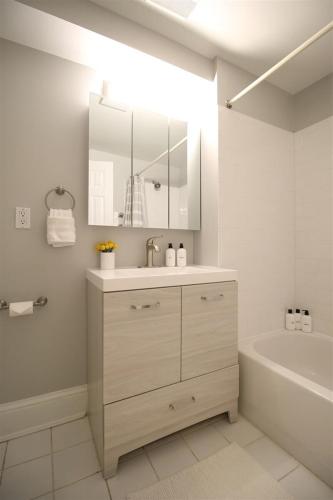 a white bathroom with a sink and a bath tub at Lincoln Park Place Capitol Hill with Parking in Washington, D.C.