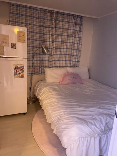 a bed in a room next to a refrigerator at Hey, World Stay SEOUL in Seoul