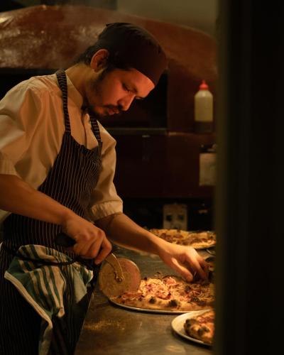a man in a kitchen preparing pizzas on a counter at Daylesford Hotel in Daylesford